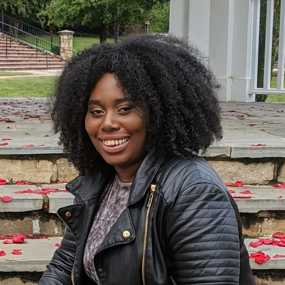 A black woman sitting on steps with red roses.